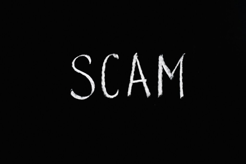pexels-photo-5697260-5697260 Chalk-drawn text 'SCAM' on black background, representing fraud and deception.