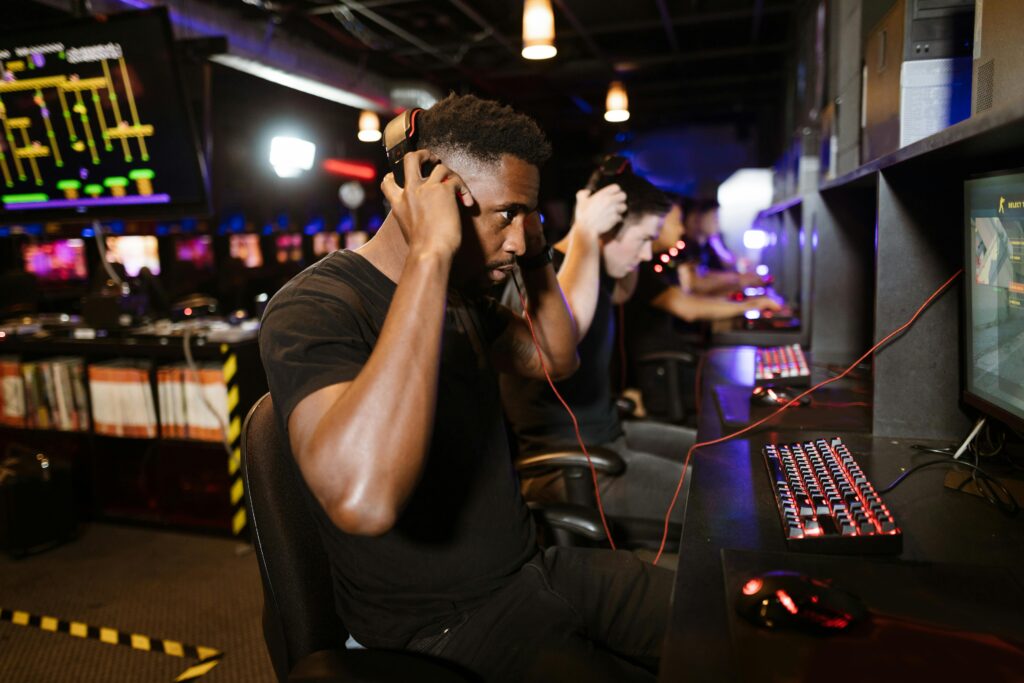 pexels-photo-7915231-7915231 Focused gamers with headphones immersed in PC games at a lively esports venue.